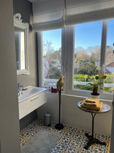 ein Bad mit einem Waschbecken, einem Tisch und Fenstern in der Unterkunft Villa Léoval sur le port du Pouliguen in Le Pouliguen