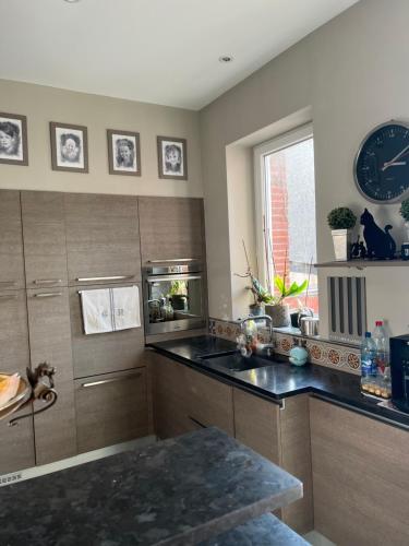 une cuisine avec un évier et une horloge murale dans l'établissement Villa Léoval sur le port du Pouliguen, au Pouliguen