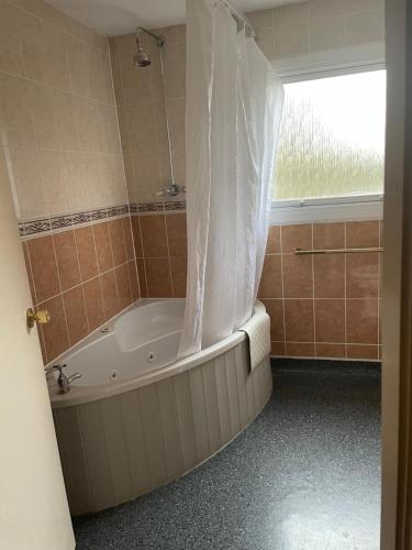 a bath tub in a bathroom with a window at The Conningbrook Hotel in Ashford