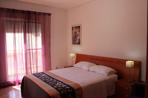 ein Schlafzimmer mit einem Bett mit zwei Lampen und zwei Fenstern in der Unterkunft Casa para vacaciones o estancias cortas in Barrio de las Cuevas