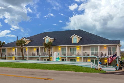 a large building with a flag in front of it at Ocean Sands Beach Boutique Inn-1 Acre Private Beach-St Augustine Historic-2 Miles-Shuttle with Downtown Tour-HEATED Salt Water Pool until 420AM-Popcorn-Cookies-New 4k USD Black Beds- 69 Item Breakfast-Eggs-Bacon-Starbucks- Free Laundry- #904-799-SAND in Saint Augustine
