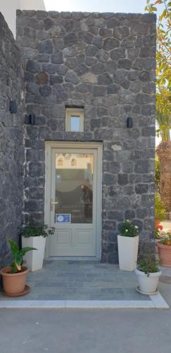 a stone building with a door and two potted plants at Atlas Pension in Karterados