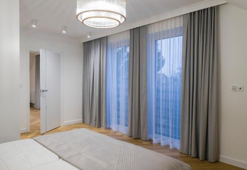 1 dormitorio con 1 cama y ventanas grandes en Apartamenty nad Zalewem ARKADIA w Suwałkach en Suwałki