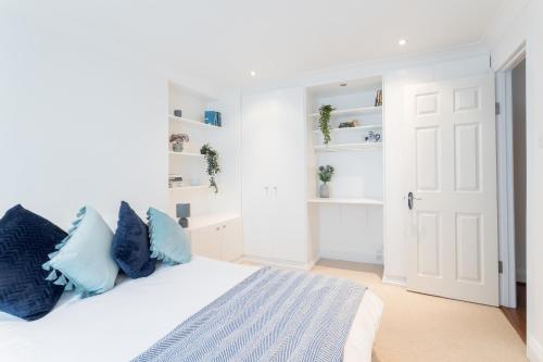 a white bedroom with a bed with blue pillows at Beautiful Home in Camden with Garden in London