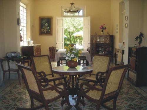 a dining room with a table and chairs and a kitchen at La Casa del Turix in Mérida