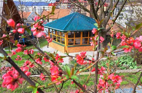 a building with a blue roof in a garden with pink flowers at Bosnian Villa in Hadžići