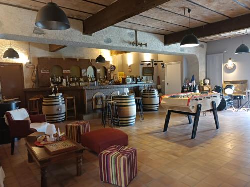 a large room with a table and a bar with barrels at Gîte proche des passerelles et du lac de Monteynard 