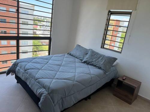 a bedroom with a bed with a blue comforter and two windows at Fresco, cómodo y Amplio! in Neiva