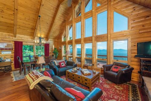 a living room with couches and a flat screen tv at Above the Clouds Log Cabin, Hot Tub & Views! in Old Fort