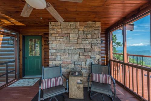 two chairs on a porch with a stone wall at Above the Clouds Log Cabin, Hot Tub & Views! in Old Fort