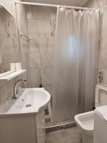 a white bathroom with a shower and a sink at Cozy Studio in Athens