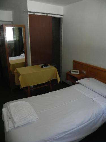 a room with two beds and a table and a mirror at Hotel Nuovo Pecetto in Macugnaga