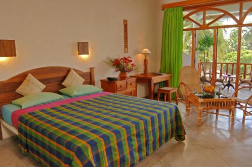 本托塔的住宿－Wunderbar Beach Hotel，卧室配有一张床和一张桌子及椅子