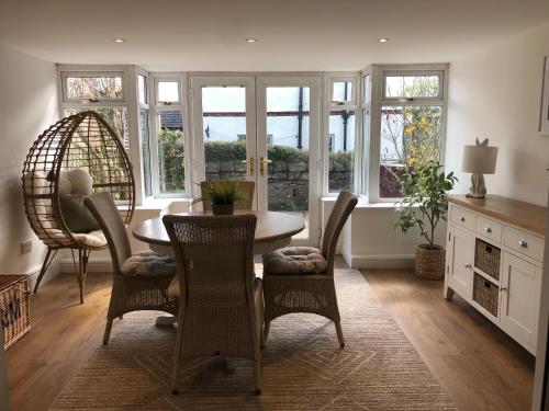 a dining room with a table and chairs and windows at Honeybee Cottage, Waddington in Waddington