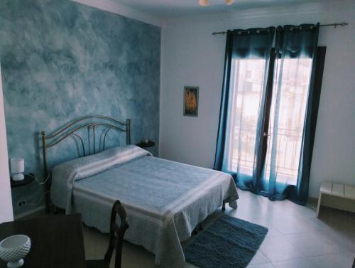 a bedroom with a bed with blue walls and a window at Granello di Sabbia in San Vito lo Capo