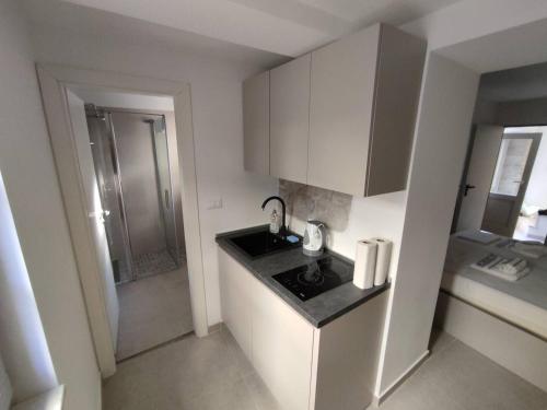 a small white kitchen with a sink and a shower at The center of Split, renovated stone house in Split