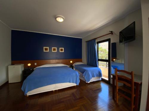 2 camas en un dormitorio con una pared azul en Minas Garden Hotel, en Poços de Caldas