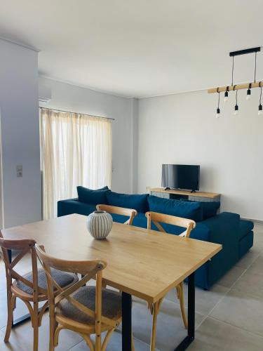 a living room with a table and a blue couch at SunRise Apartment near Airport in Spata