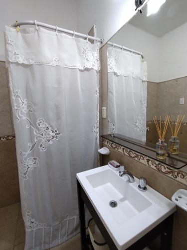 baño con cortina de ducha blanca y lavamanos en Departamento Urquiza en San Juan