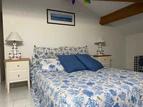 - une chambre avec un lit bleu et blanc et 2 tables de chevet dans l'établissement Coudoulière vue mer, à Six-Fours-les-Plages