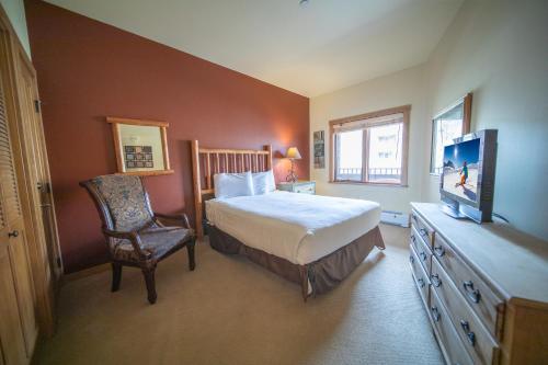 1 dormitorio con 1 cama, 1 silla y TV en Arapahoe Lodge 8116, en Keystone