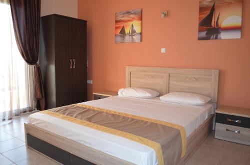 リメナリアにあるThassos Grand Villas Apartments & Studiosのベッドルーム1室(オレンジ色の壁の大型ベッド1台付)