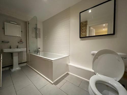 a bathroom with a toilet and a tub and a sink at Entire 2-bedroom Flat in Camden in London