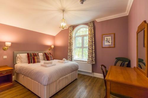 a bedroom with a bed and a desk and a window at Redwings Sanctuary Rooms - Norfolk Holiday Properties 