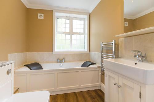 a bathroom with a tub and a sink and a window at Redwings Sanctuary Rooms - Norfolk Holiday Properties 