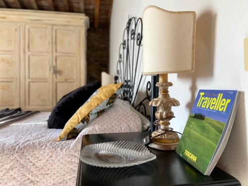 uma mesa com um candeeiro e um livro sobre uma cama em Casa Malù Suvereto Antica Dimora with two bedrooms em Suvereto