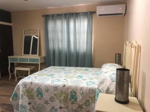 a bedroom with a bed and a desk with a mirror at Casa Coral in Progreso in Progreso