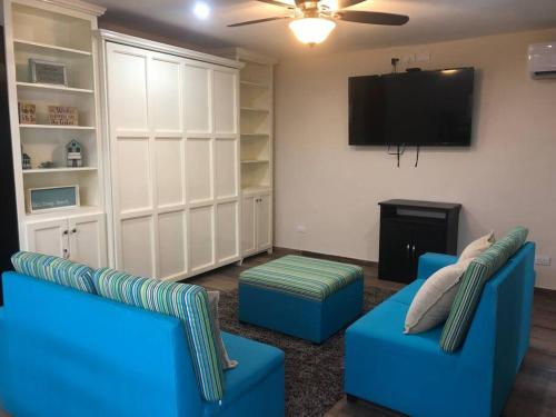 a living room with two blue chairs and a flat screen tv at Casa Coral in Progreso in Progreso