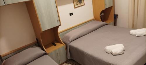 two beds in a small room with towels on them at Villa Lavinia in Rimini