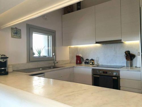 a kitchen with white cabinets and a counter top at Villa Gaia in Sarakíniko