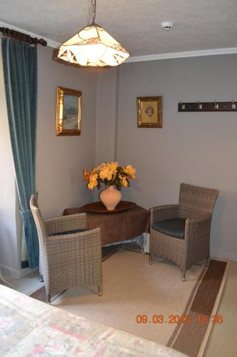 a living room with chairs and a table with a vase of flowers at Auberge Au Naturel des Ardennes in Rochehaut