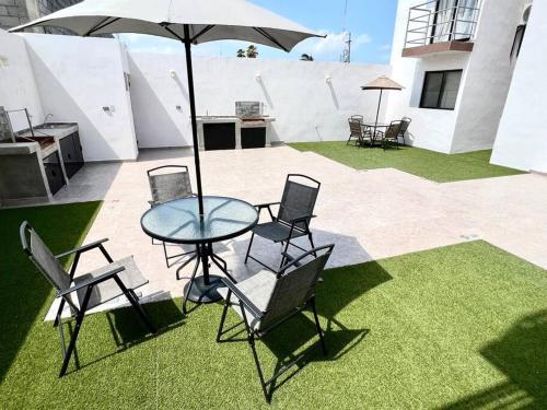 - une table en verre avec des chaises et un parasol sur la terrasse dans l'établissement Luxury Apartment with Great Location 2-A, à Matamoros