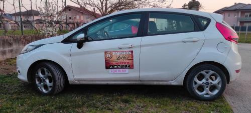 a white small car parked in the grass at Pansion Laktaši in Laktaši
