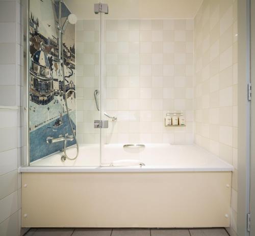 a bathroom with a bath tub with a picture on the wall at Holiday Inn Oxford by IHG in Oxford