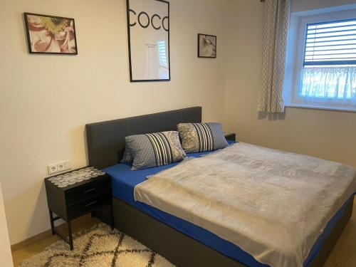 1 dormitorio con cama con sábanas azules y ventana en Wohnung City Nord mit Balkon, en Herzogsdorf