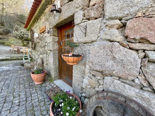 um edifício de pedra com vasos de plantas em frente a uma porta em Moinho de Brião em Montalegre