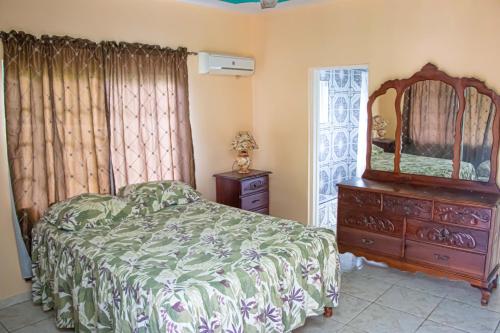 a bedroom with a bed and a dresser and a mirror at Charlie's Cottages in Negril