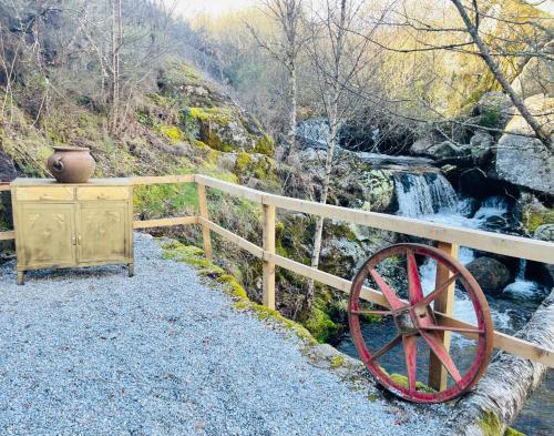 a wooden fence with a wheel next to a waterfall at Moinho de Brião in Montalegre