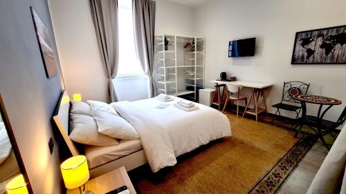 sypialnia z białym łóżkiem, stołem i biurkiem w obiekcie Fortuna Guest House w Syrakuzach