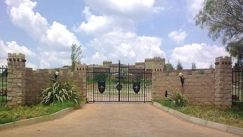a gate in a brick wall with a driveway at Castelo Sutil Guest House in Bloemfontein