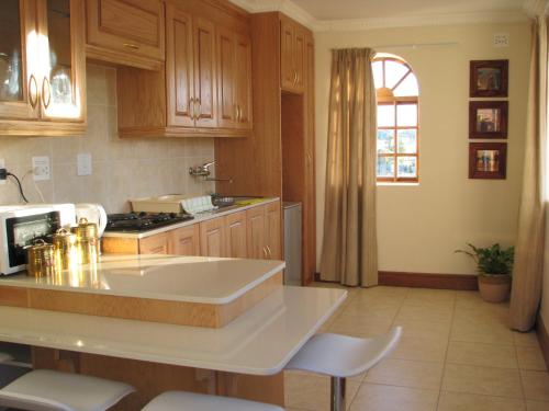 a kitchen with wooden cabinets and a white counter top at Castelo Sutil Guest House in Bloemfontein
