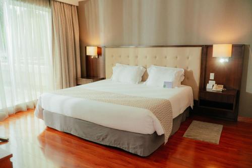 a bedroom with a large white bed with a large window at Aparta Hotel Torres de Suites in Quito