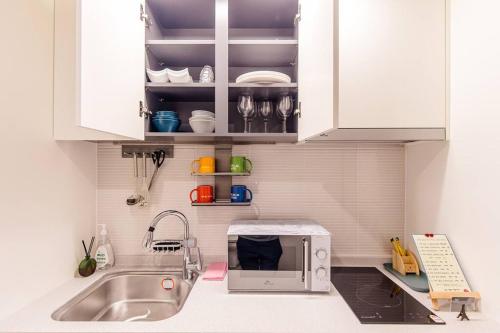 eine Küche mit einer Spüle und einer Mikrowelle in der Unterkunft The Castle Ocean Marina Double Suite in Yeosu