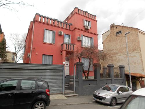 a red house with cars parked in front of it at Guest House Miss Depolo in Belgrade