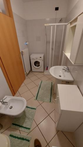 La salle de bains est pourvue de 2 lavabos et d'un lave-linge. dans l'établissement Appartamento Alessandro, à Pergine Valsugana