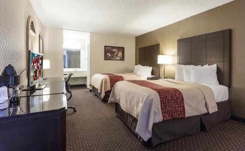a hotel room with two beds and a desk at Red Roof Inn & Suites DeKalb in DeKalb